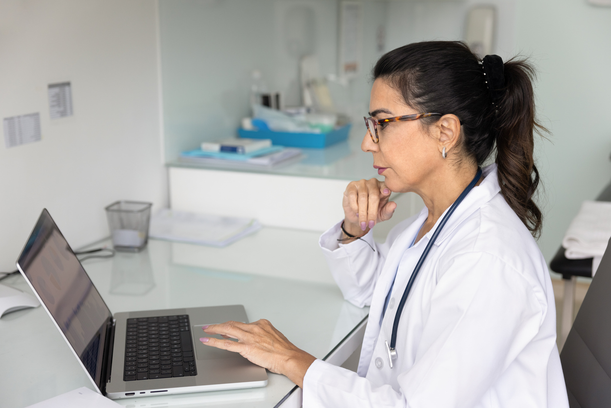 Doctor Sitting At Desk Working On Laptop